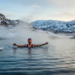 Norsk person som kommer opp fra iskaldt fjord om vinteren med damp stigende fra vannet