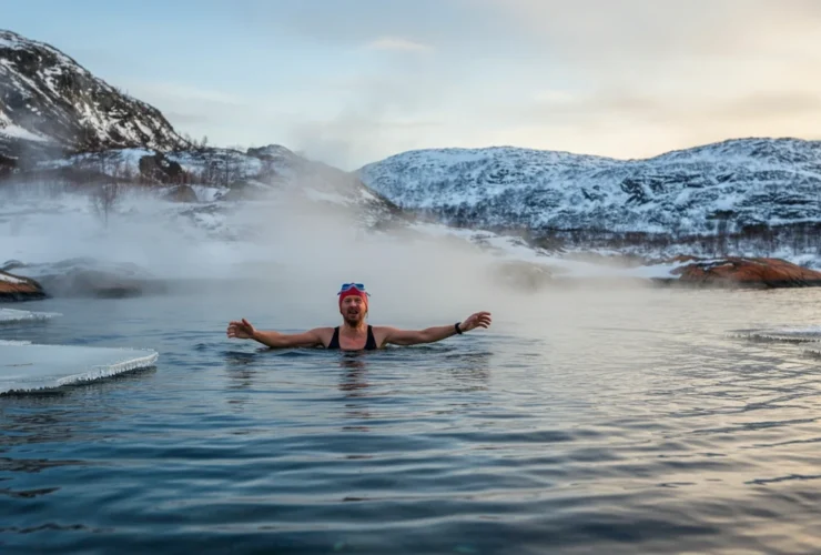 Norsk person som kommer opp fra iskaldt fjord om vinteren med damp stigende fra vannet