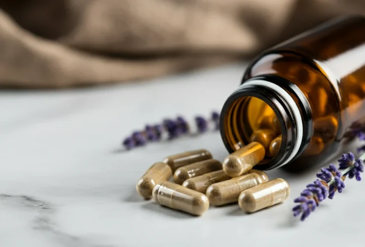 Magnesium glysinat kapsler fra ravfarget flaske på hvit marmor med lavendel