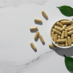 Magnesium malat og glysinat kapsler på hvit marmor med grønne blader