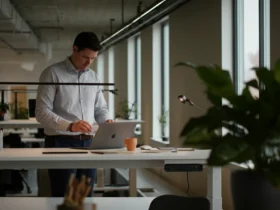 Norsk kontorarbeider ved hevsenk skrivebord i lyst moderne nordisk kontor
