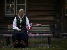 Sliten forelder i bunad sitter alene på en benk om kvelden, et bilde på 17 mai tretthet
