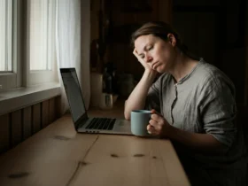 Kvinne med hjernetåke som stirrer tomt forbi laptopen ved skrivebordet