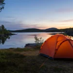 Telt satt opp ved en stille norsk innsjø i skumring, klart for å sove i telt